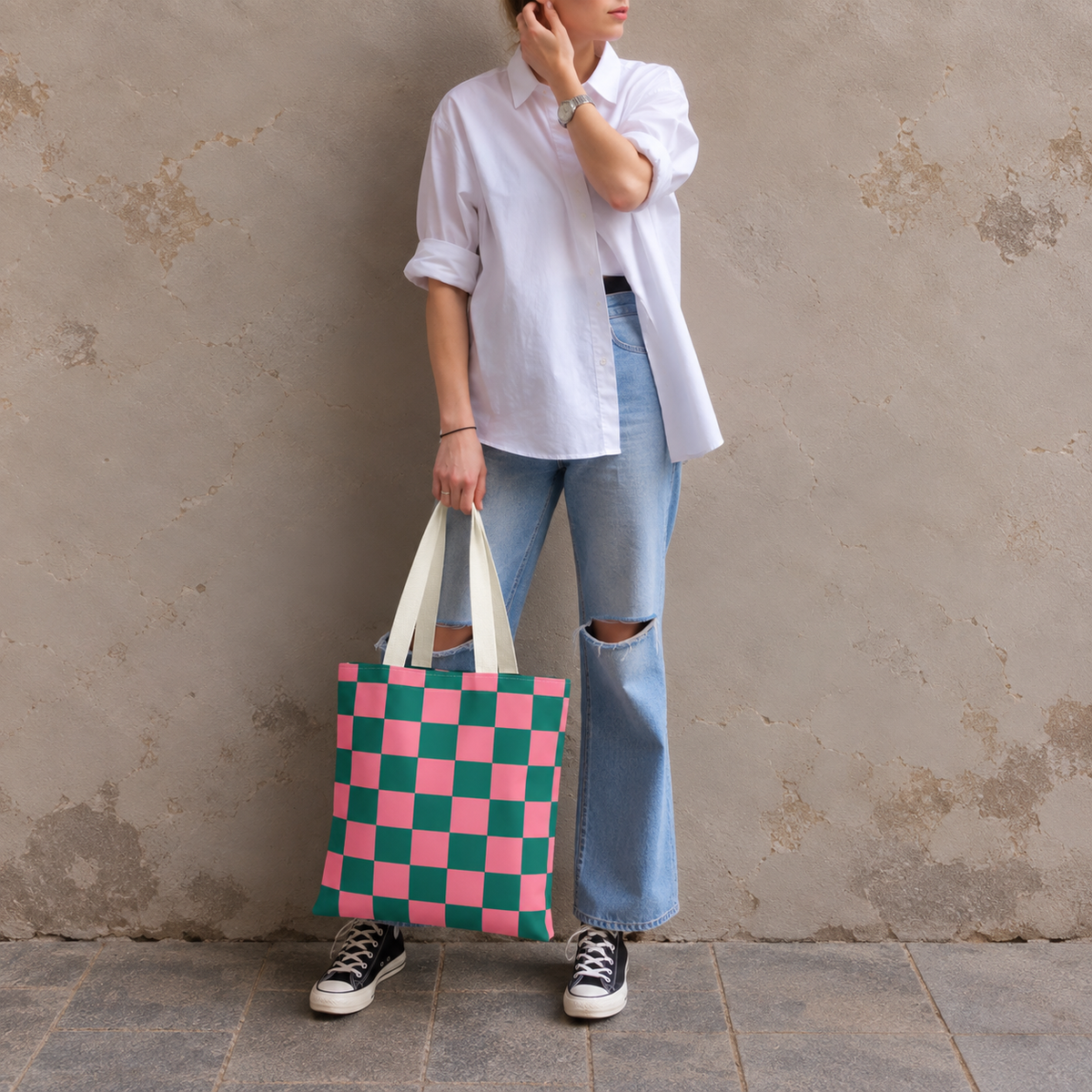 Woman in a white shirt and jeans standing with the pink green checkered tote bag