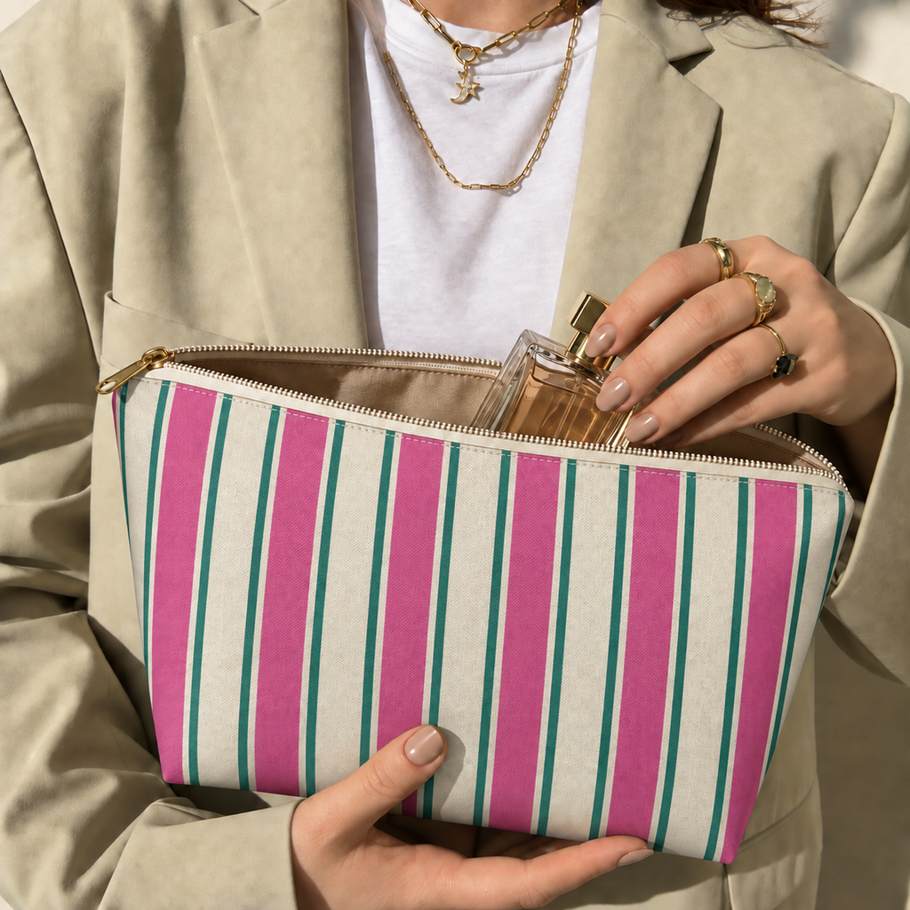 Hands holding the open Pink Green Cream Striped makeup bag filled with cosmetics
