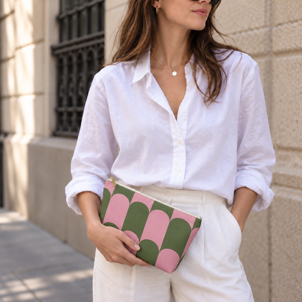 Model in a white shirt holding the pink green scallop makeup bag as a clutch