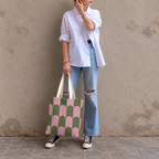 Model in jeans and a white shirt standing with the pink green scallop tote bag