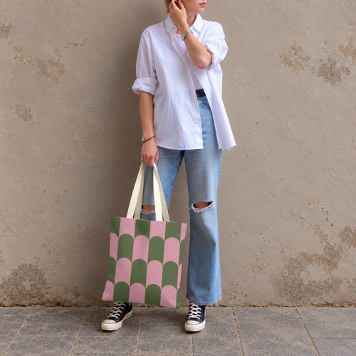 Model in jeans and a white shirt standing with the pink green scallop tote bag