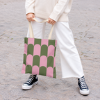 Model holding the pink green scallop tote bag in front of white trousers