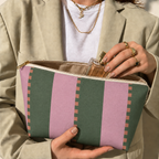 Open pink green striped makeup bag held in hands