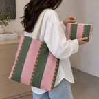 Woman carrying the pink green striped tote bag with a matching pouch