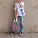 Woman in a white shirt and jeans holding the pink green zebra print tote bag