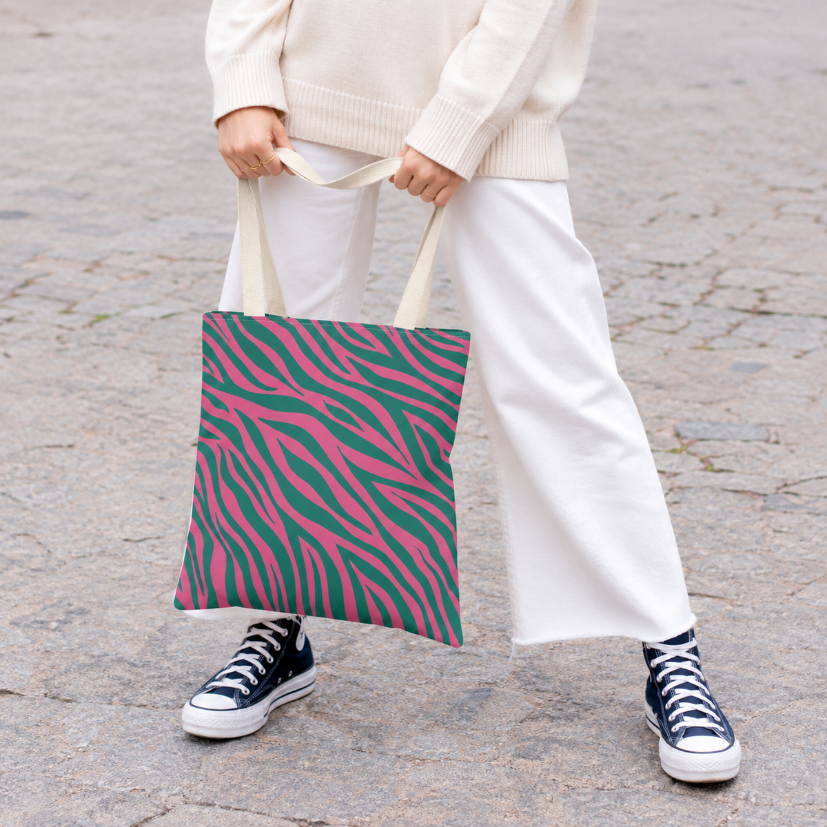 Woman in white trousers and sneakers holding the zebra print tote bag