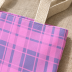 Close-up of the pink and lavender plaid print and cream handle of the tote bag