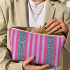 Hands holding the open Pink Leopard Striped makeup bag filled with cosmetics