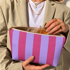 Hands holding the open Pink Lilac Striped makeup bag filled with cosmetics