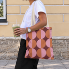 Pink orange geometric tote bag worn on the shoulder with an iced drink