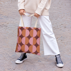 Model holding the pink orange geometric tote bag with white trousers