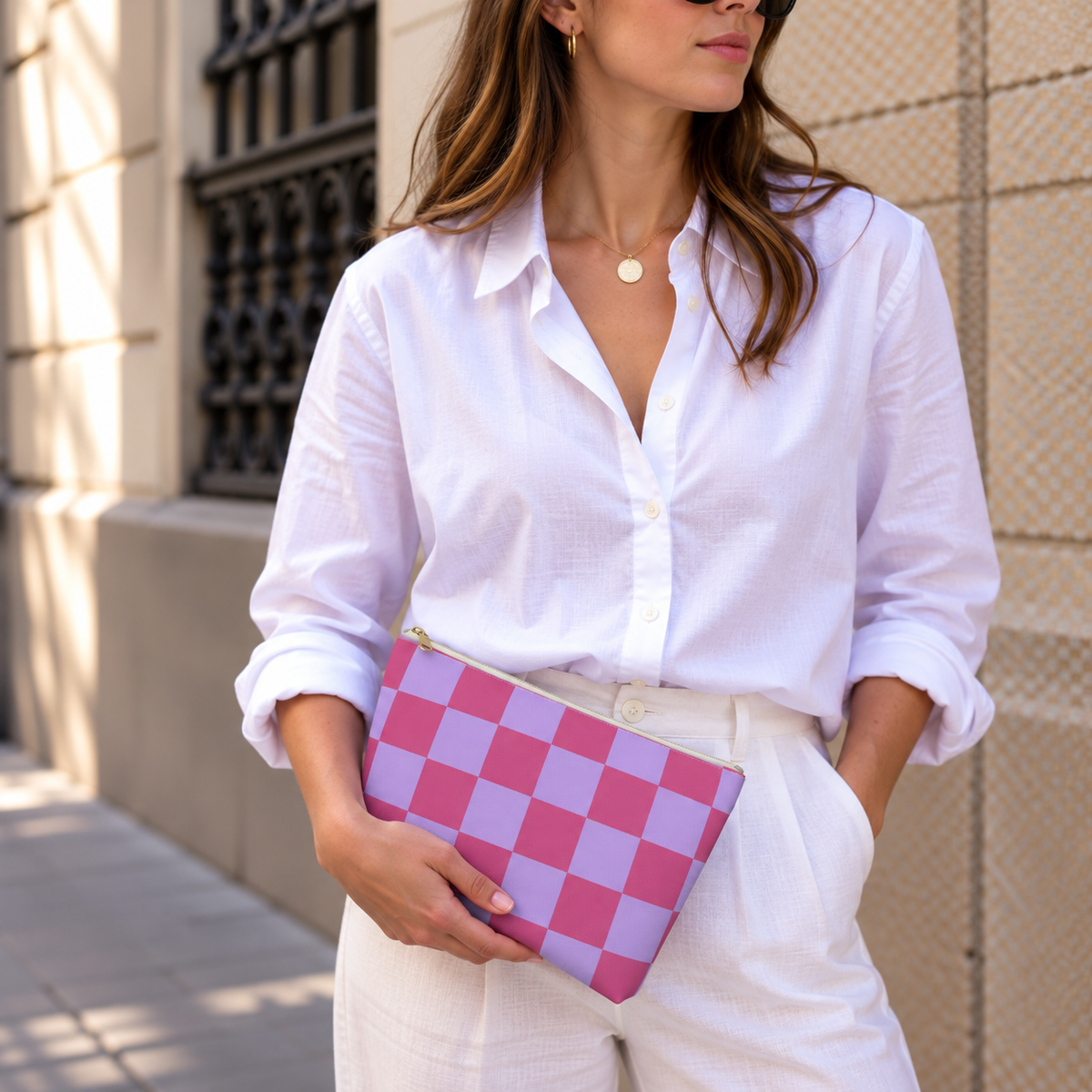 Woman in a white shirt holding the pink purple checkered makeup bag as a clutch