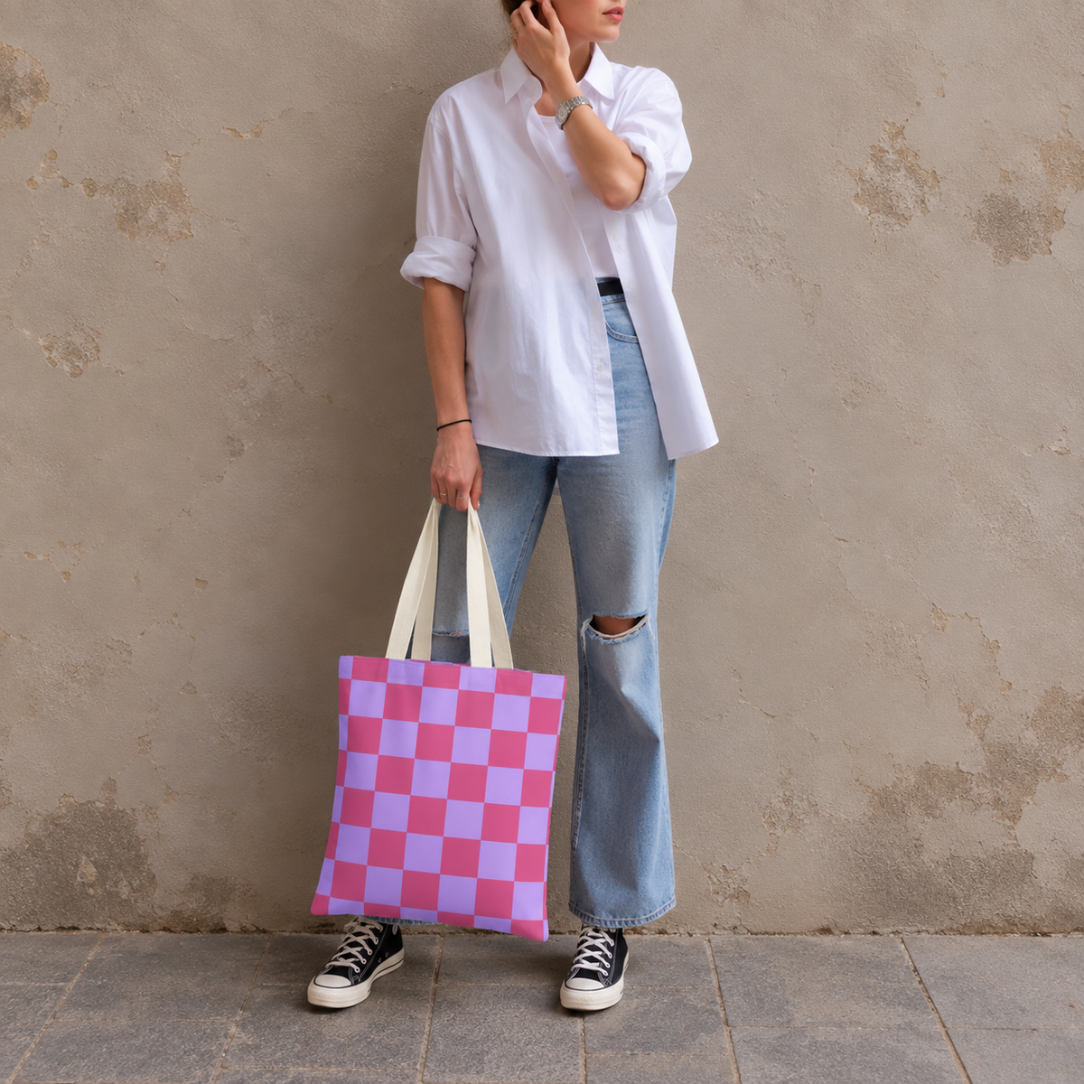 Woman standing in jeans and a white shirt with the pink purple checkered tote bag