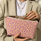 Hands holding the pink purple leopard print makeup bag with a perfume bottle inside