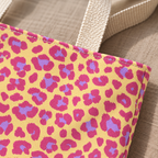 Close-up of pink and purple leopard spots on yellow next to the beige tote handle