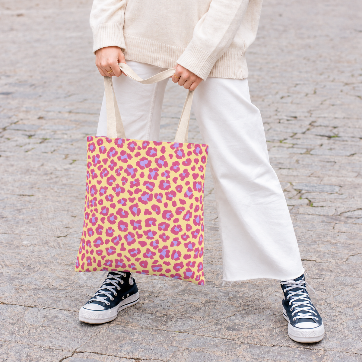 Woman in white trousers carrying the pink purple leopard print tote bag