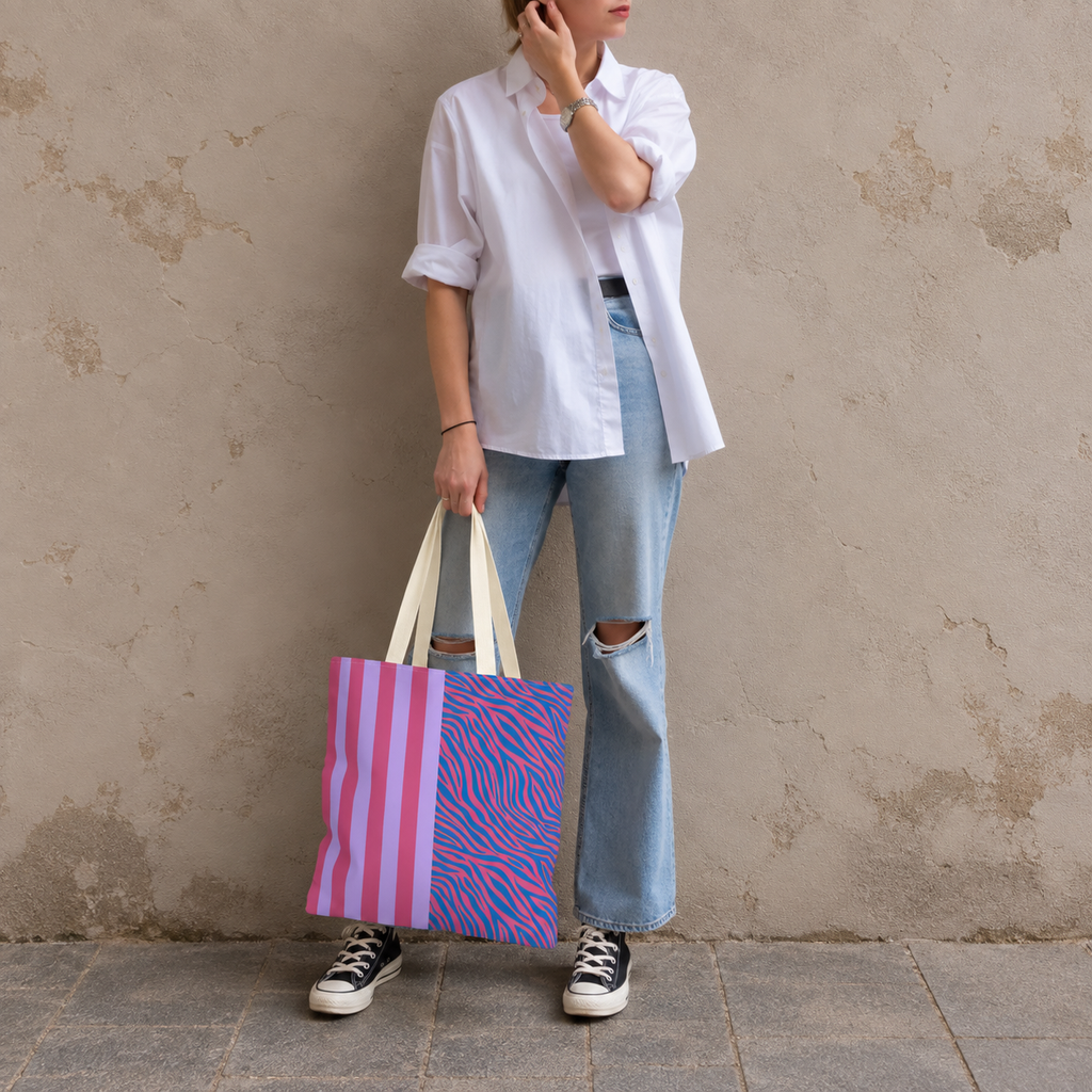 Woman in a white shirt and jeans holding the pink purple zebra stripe tote bag