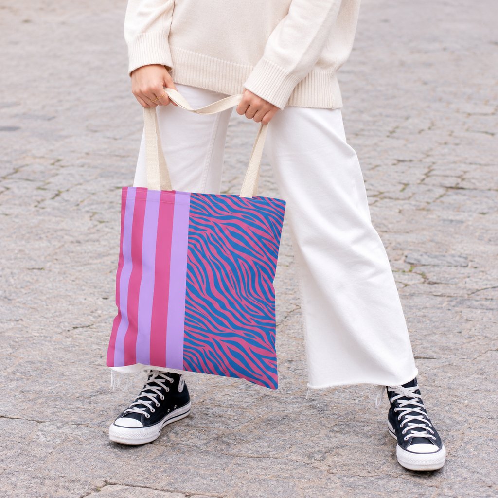 Woman in white trousers and sneakers holding the pink and lilac zebra stripe tote bag