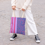 Woman in white trousers and sneakers holding the pink and lilac zebra stripe tote bag
