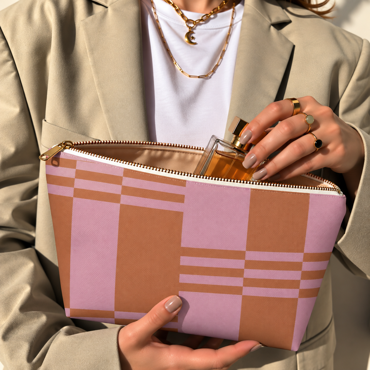 Model in a beige blazer taking a product out of the open pink terracotta color block makeup bag