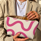Woman holding the pink wavy line makeup bag open with the gold zipper