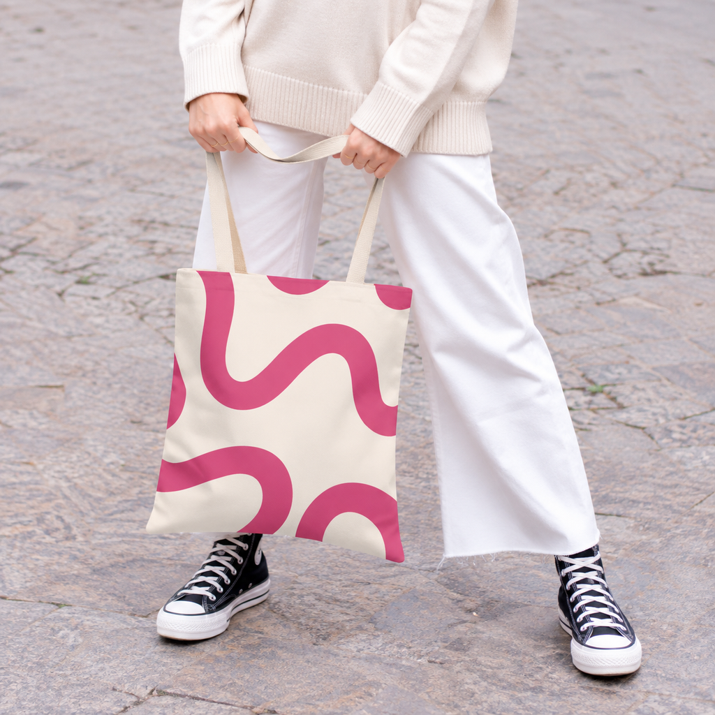 Woman in white trousers holding the pink wavy line tote bag by the handles