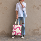 Woman standing in jeans and a white shirt with the pink wavy line tote bag