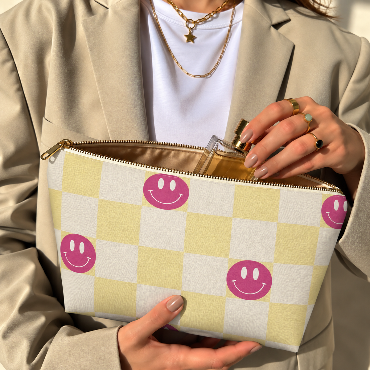 Woman holding the pink yellow smiley checkered makeup bag open with the gold zipper