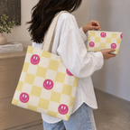 Woman holding the pink yellow smiley checkered tote bag and matching makeup bag