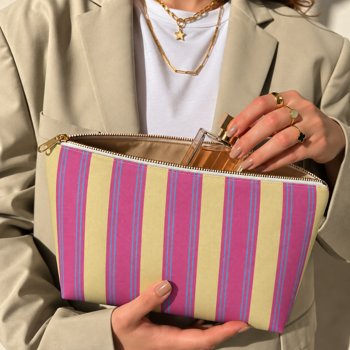 Hands holding the open Pink Yellow Striped makeup bag filled with cosmetics