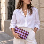 Woman in white shirt holding the purple burgundy checkered makeup bag as a clutch