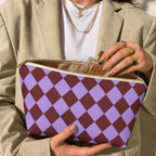 Hands holding the purple burgundy checkered makeup bag with a perfume bottle inside
