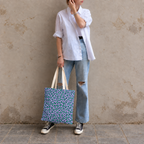 Woman in jeans and sneakers holding the purple green leopard print tote bag