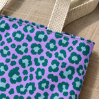Close-up of emerald green leopard spots on lavender next to the beige tote handle