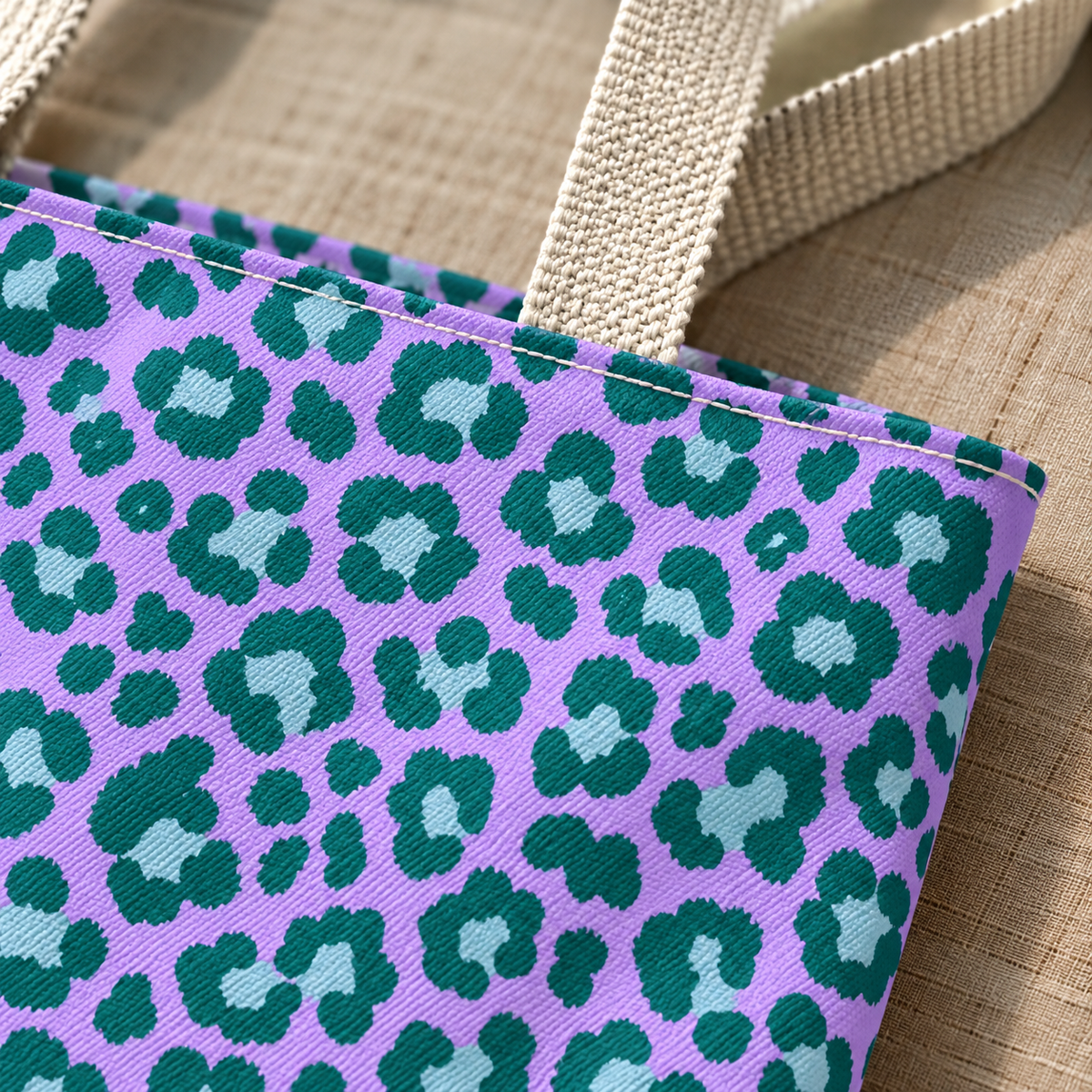 Close-up of emerald green leopard spots on lavender next to the beige tote handle