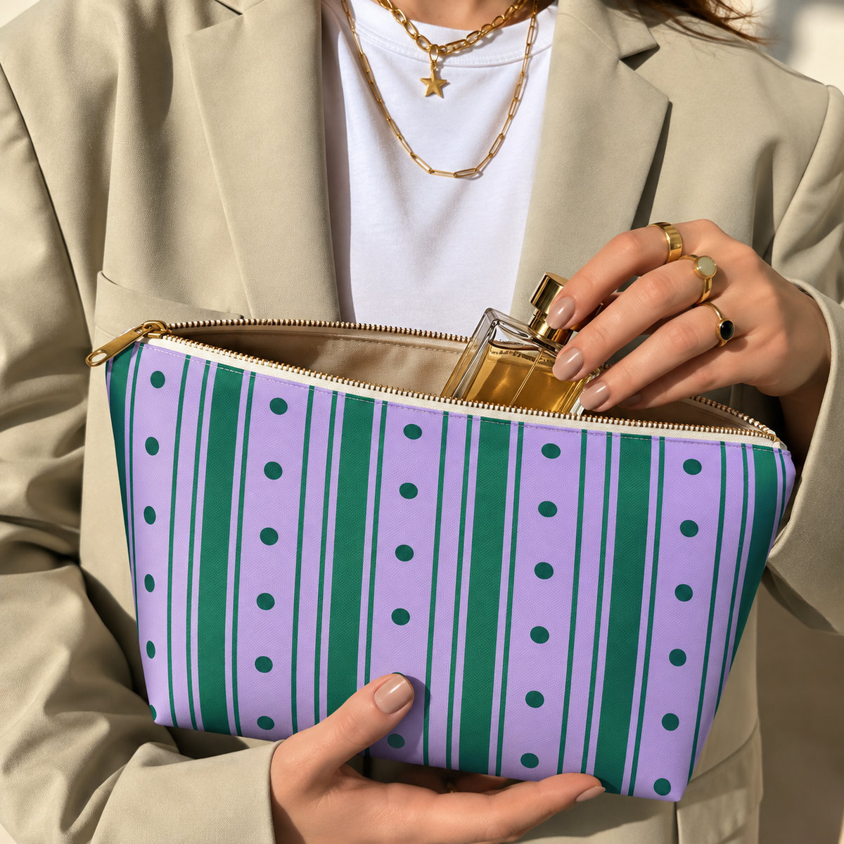 Woman holding the purple green striped makeup bag open with a perfume bottle inside