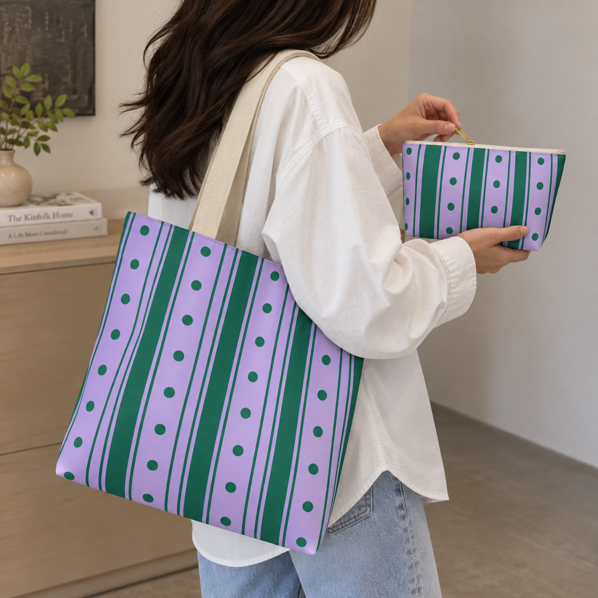 Woman carrying the purple striped tote bag next to the matching makeup bag