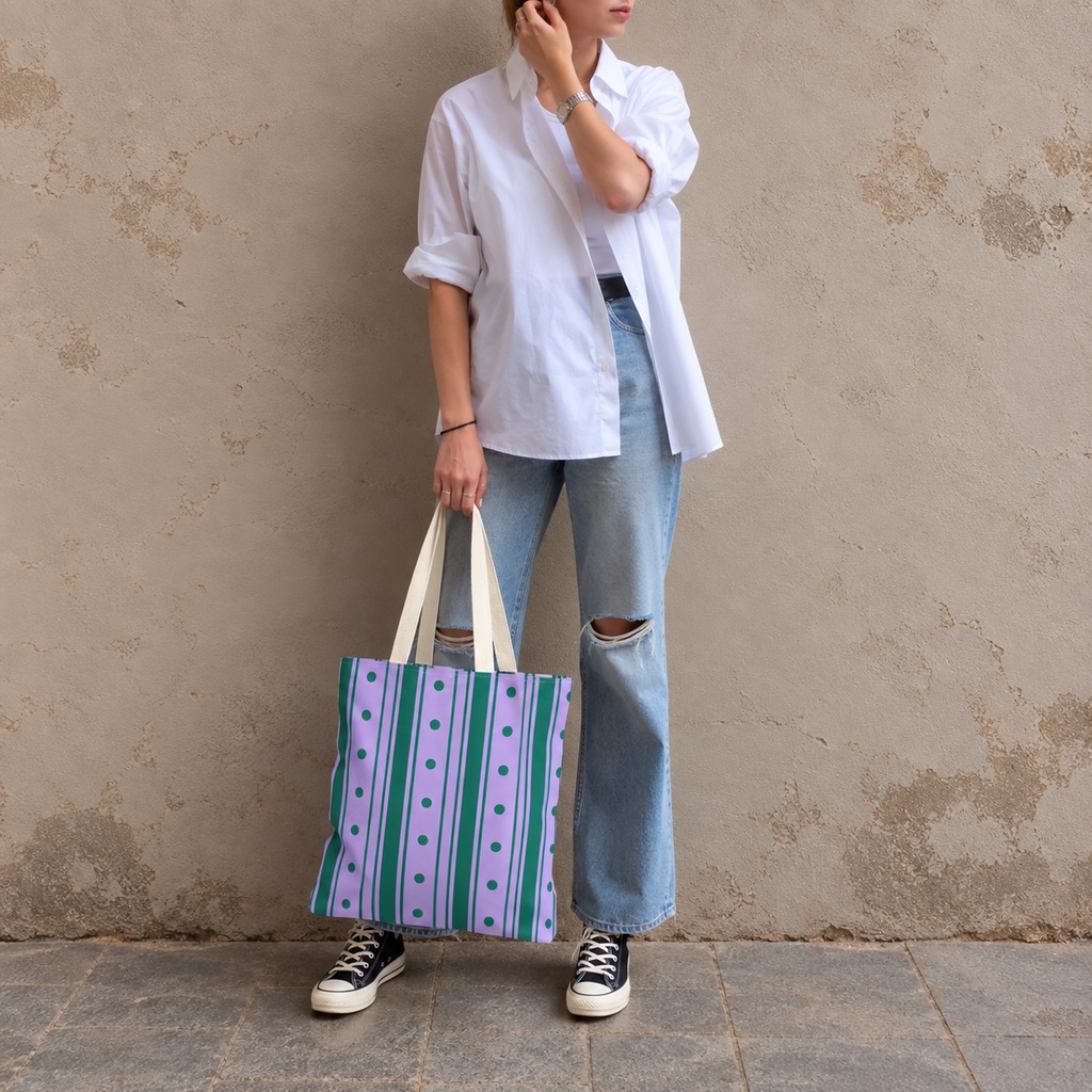 Woman in a white shirt and jeans holding the purple green striped tote bag