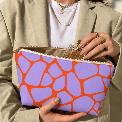 Hands holding the purple orange giraffe print makeup bag with a perfume bottle inside