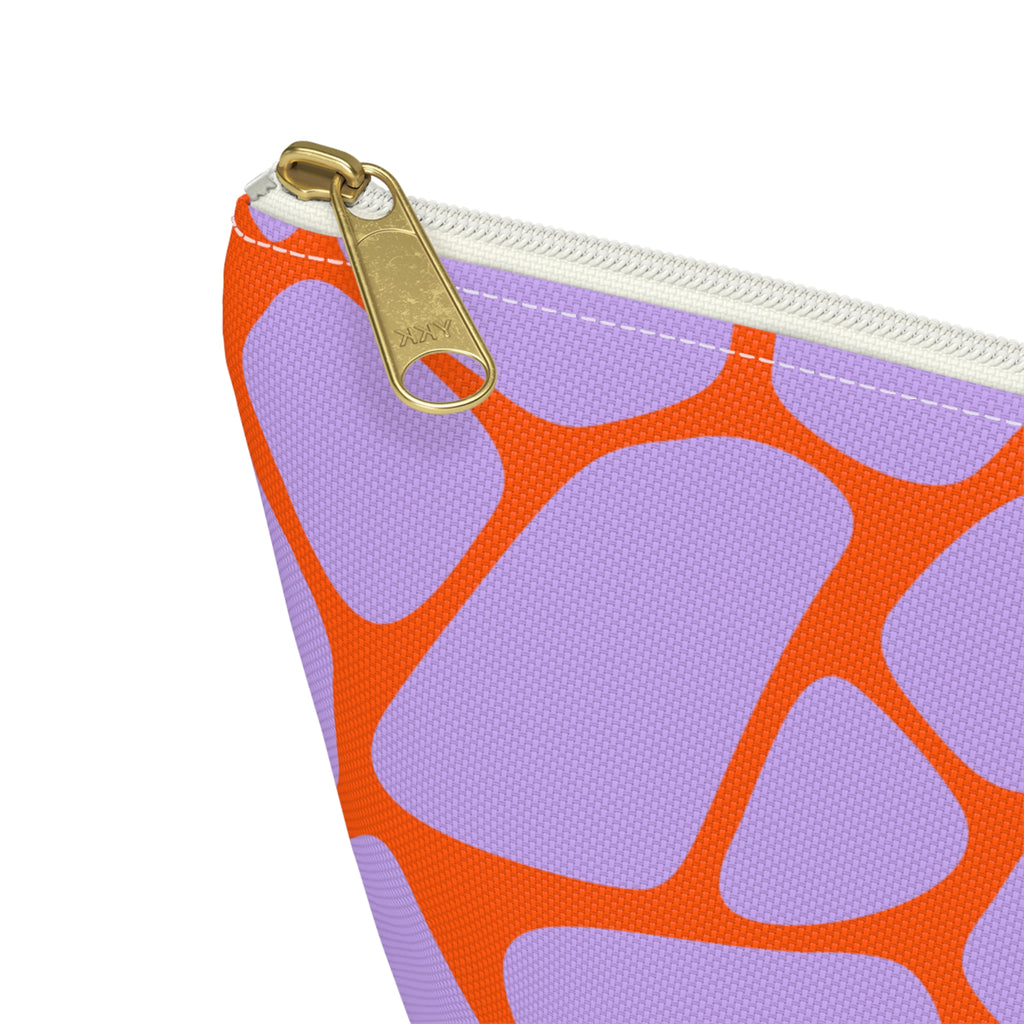 Close-up of the gold zipper pull and lilac and orange giraffe pattern on the makeup bag