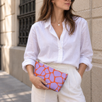 Woman in white shirt holding the purple orange giraffe print makeup bag as a clutch