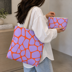 Purple orange giraffe print tote bag on the shoulder with a matching makeup bag in hand