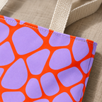 Close-up of lilac patches and orange lines next to the beige tote handle