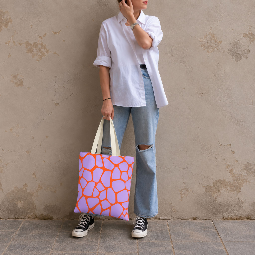 Woman in jeans and sneakers holding the purple orange giraffe print tote bag