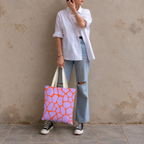Woman in jeans and sneakers holding the purple orange giraffe print tote bag