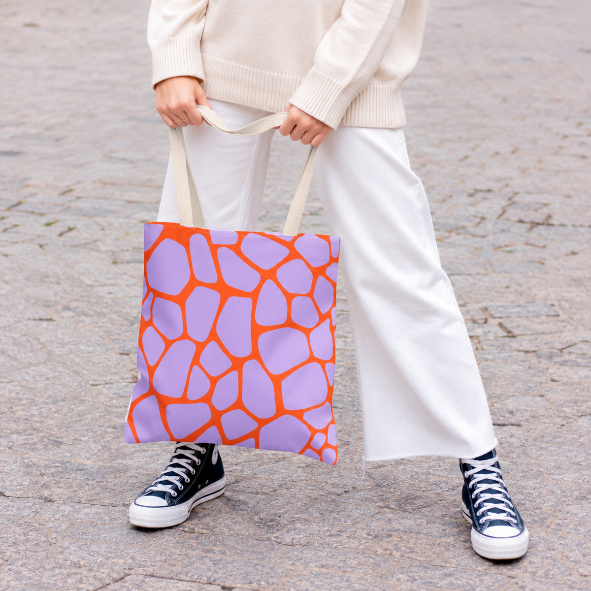 Woman in white trousers carrying the purple orange giraffe print tote bag