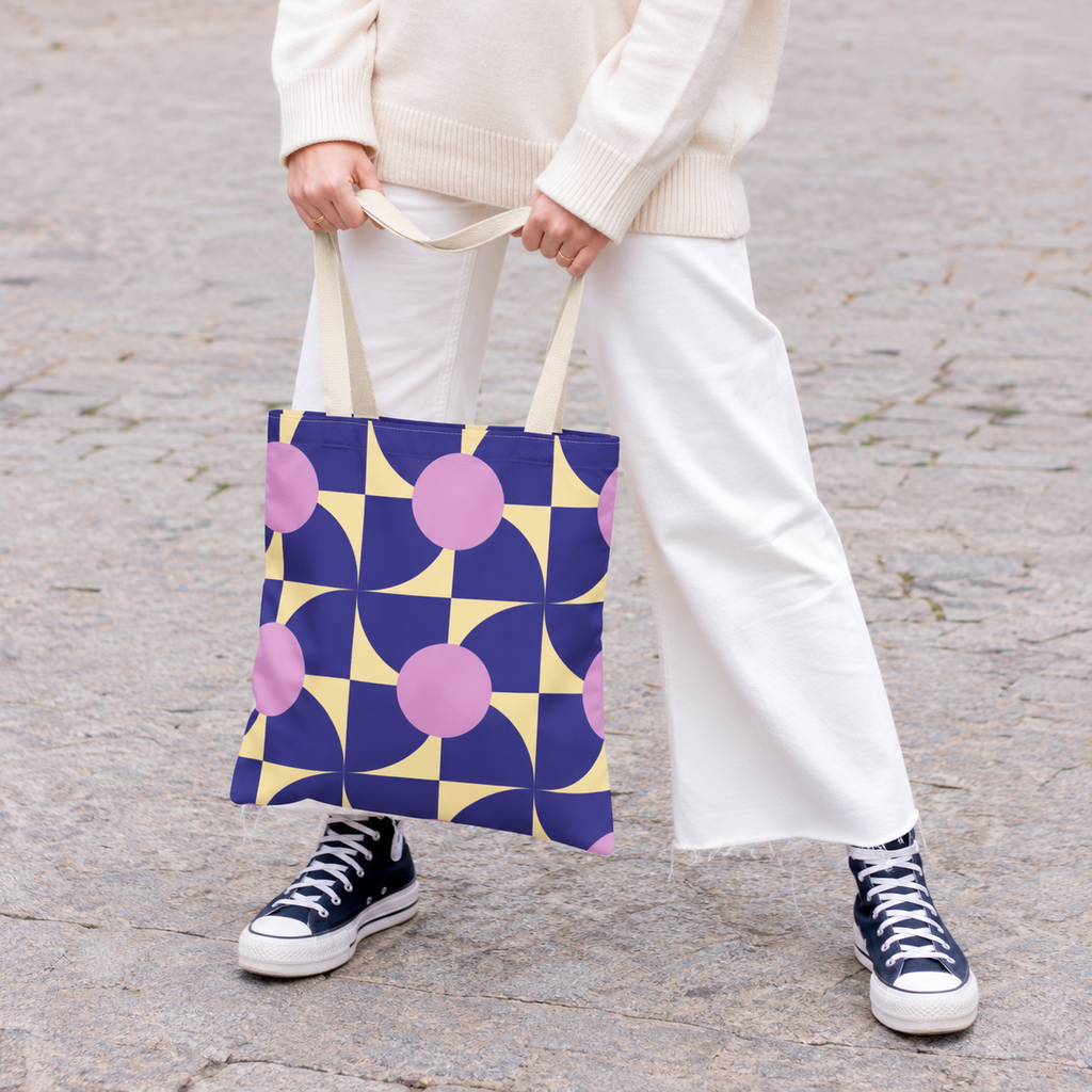 Woman in white trousers holding the purple pink geometric tote bag by the handles