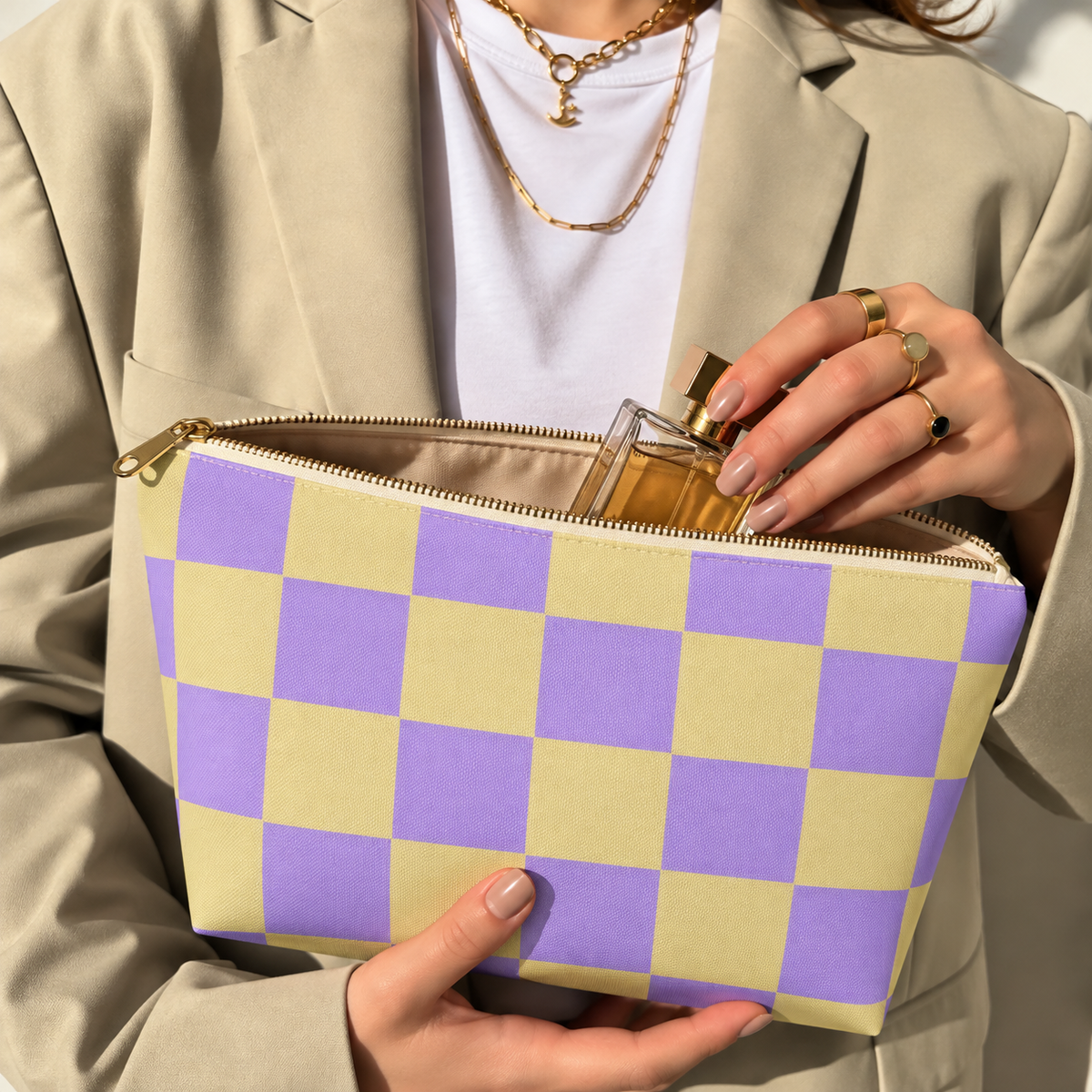 Woman holding the purple yellow checkered makeup bag open with the gold zipper
