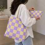 Woman holding the purple yellow checkered tote bag and matching makeup bag