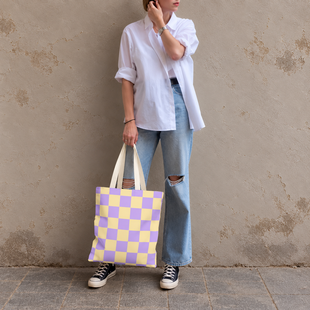 Woman standing in jeans and a white shirt with the purple yellow checkered tote bag